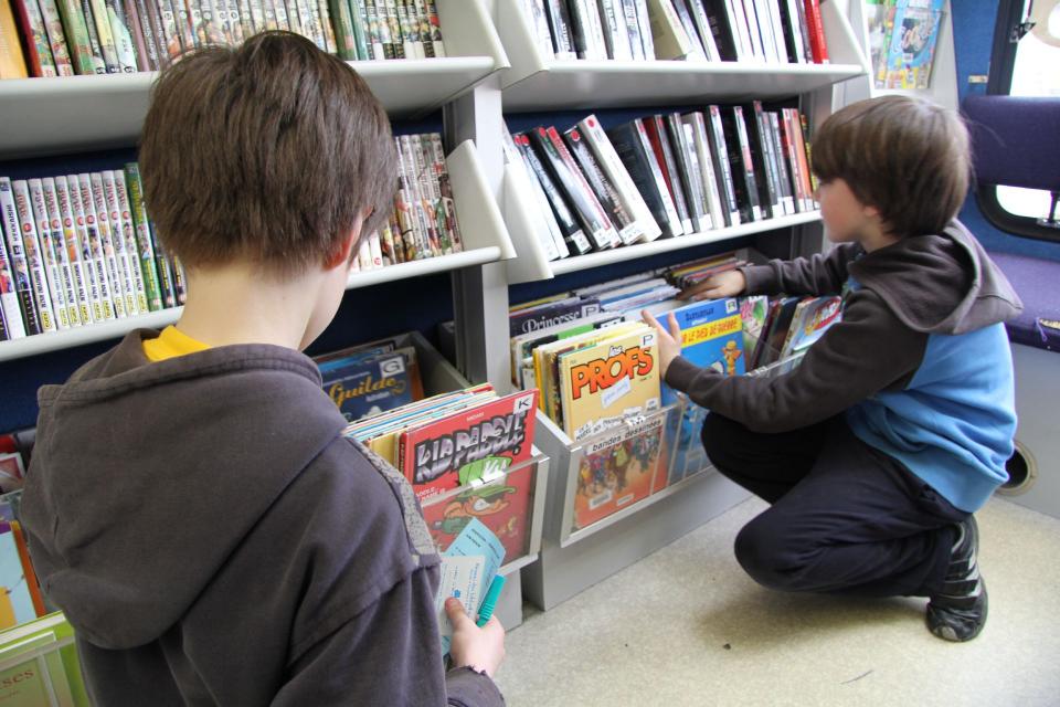 Des enfants regardent des livres sur les rayons du bouquinbus