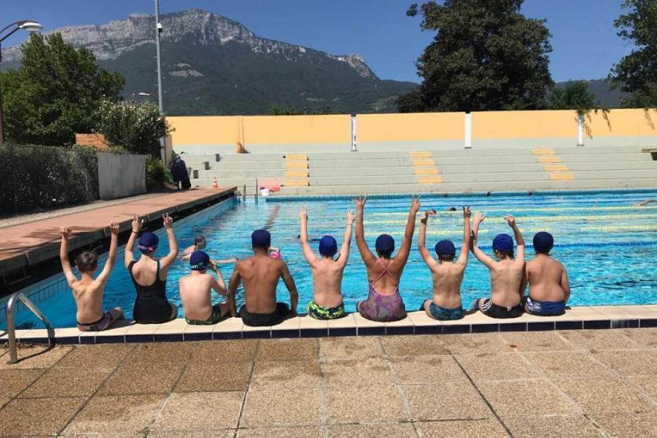 Plusieurs jeunes sont assis sur le rebord de la piscine.