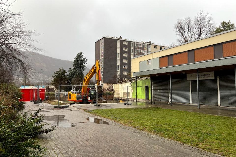 Vue sur un espace en travaux. Un local a été démoli et nous voyons l''espace libéré entouré de barrières en attendant d'être entièrement végétalisé.