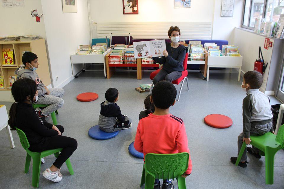 Une bibliothécaire fait une lecture à de jeunes enfants.