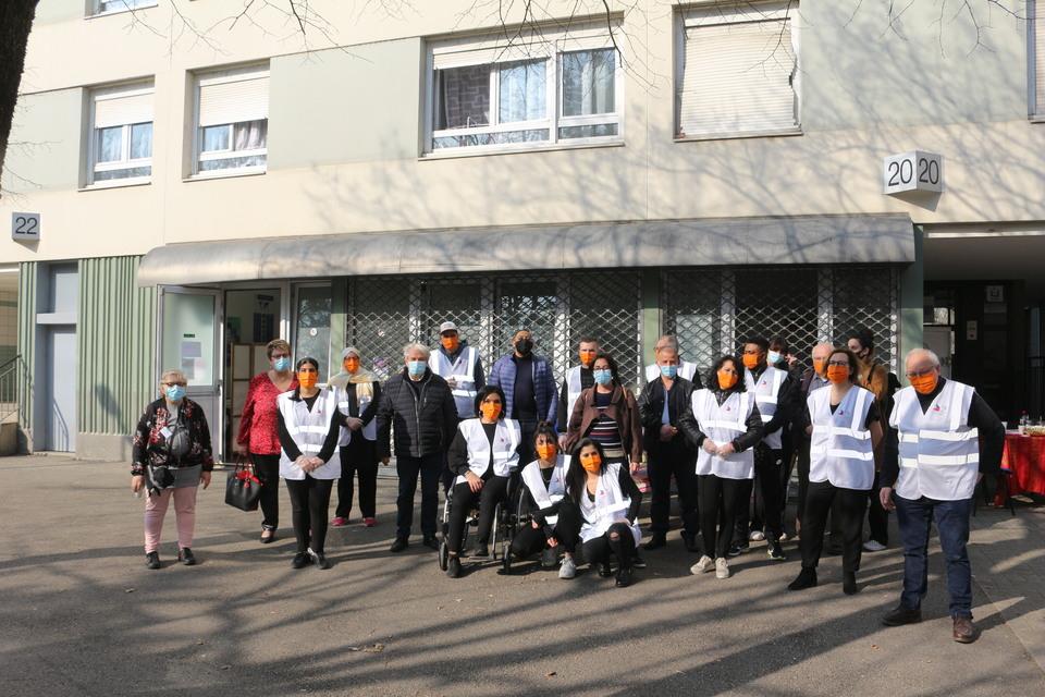 Les bénévoles du Secours Populaire posent avec les élu-es devant le lieu de la distribution alimentaire.